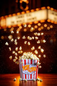 Vibrant image of popcorn exploding from a striped box in a cinematic setting.